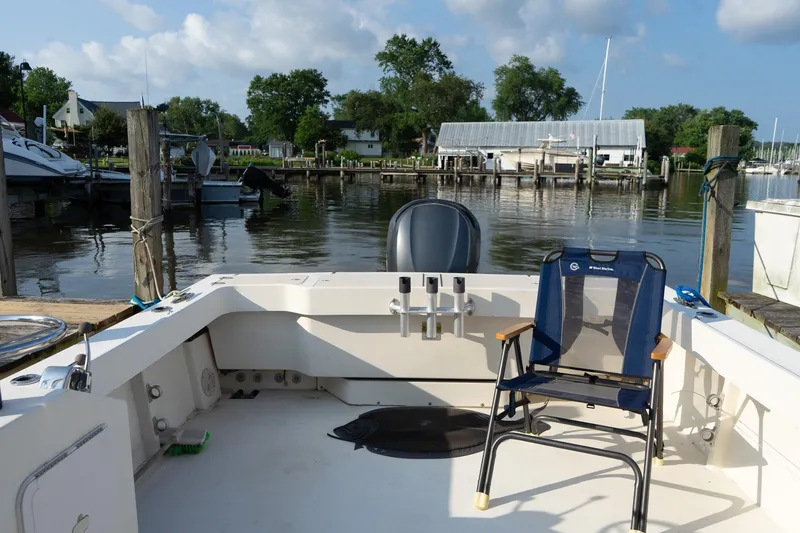 Slide: The Image of 2005 Parker 2520 Deep Vee Sport Cabin boat docked, featuring a chair and scenic marina view. - 30