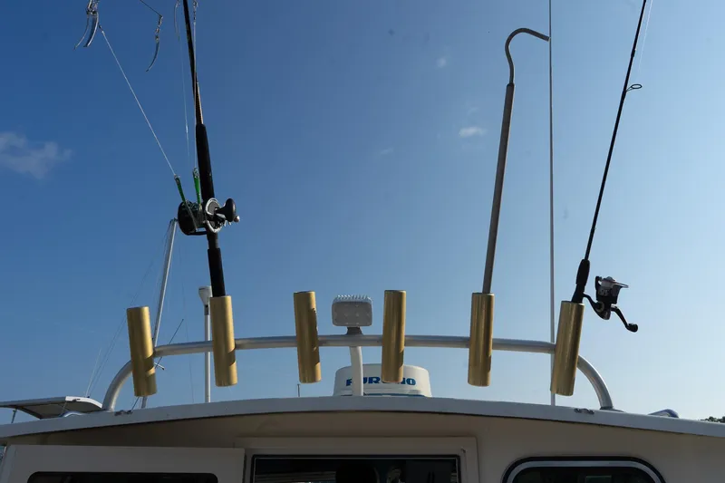 Slide: The Image of Fishing rods on a 2005 Parker 2520 Deep Vee Sport Cabin boat under clear blue sky. - 31