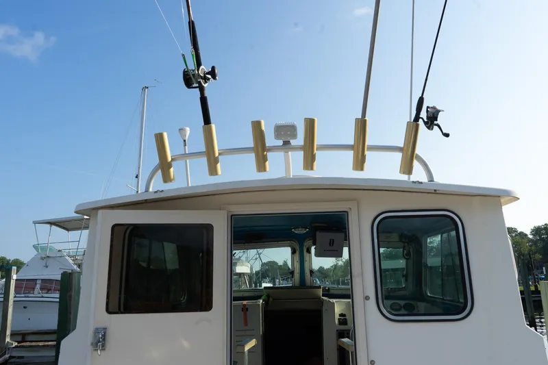 Slide: The Image of 2005 Parker 2520 Deep Vee Sport Cabin boat with fishing rods, docked at marina. - 32