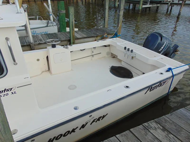 Slide: The Image of 2005 Parker 2520 Deep Vee Sport Cabin boat docked, featuring spacious deck and outboard motor. - 5
