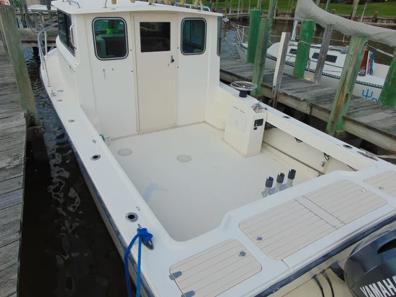 Slide: The Image of 2005 Parker 2520 Deep Vee Sport Cabin boat docked, featuring spacious deck and cabin. - 7