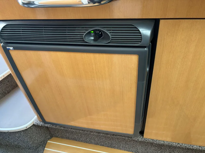 Slide: The Image of 2004 Maxum 2900 SCR boat interior with a compact wooden cabinet and integrated fridge. - 12