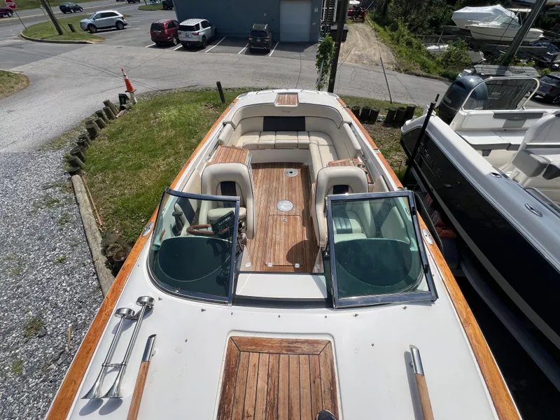 Slide: The Image of 2004 Chris-Craft Corsair 25 boat with wooden deck and seating, parked outdoors. - 3