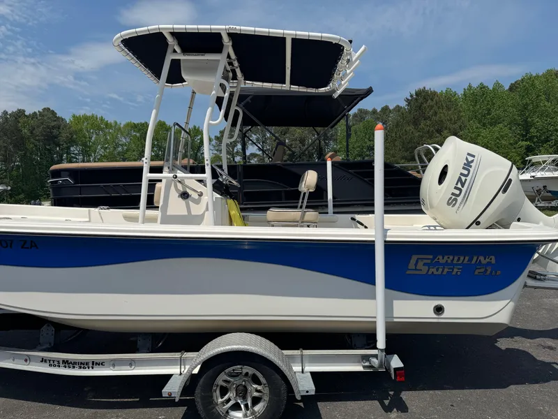 Slide: The Image of 2021 Carolina Skiff 21 LS boat with Suzuki engine on trailer, parked outdoors. - 1