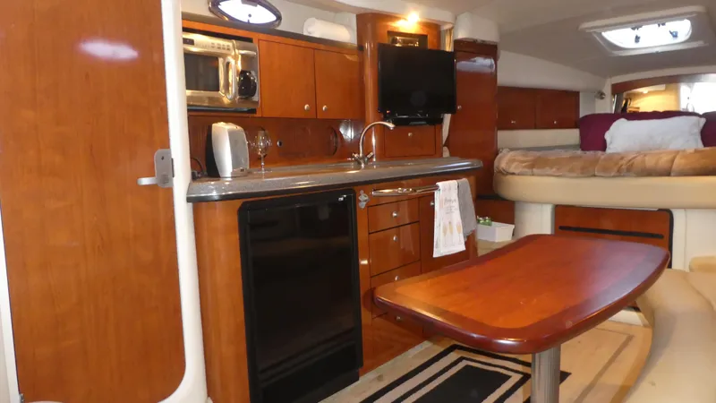 Slide: The Image of 2007 Sea Ray 340 Sundancer interior with kitchen, dining table, and cozy sleeping area. - 19