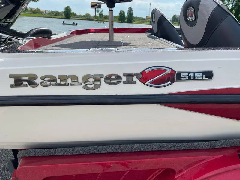 Slide: The Image of 2019 Ranger Z518L boat, red and white, on a lake with seating visible. - 2