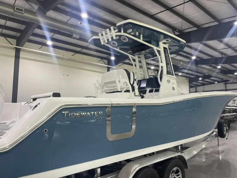 Slide: The Image of 2025 Tidewater 272 boat in showroom, blue hull, T-top, on trailer. - 1