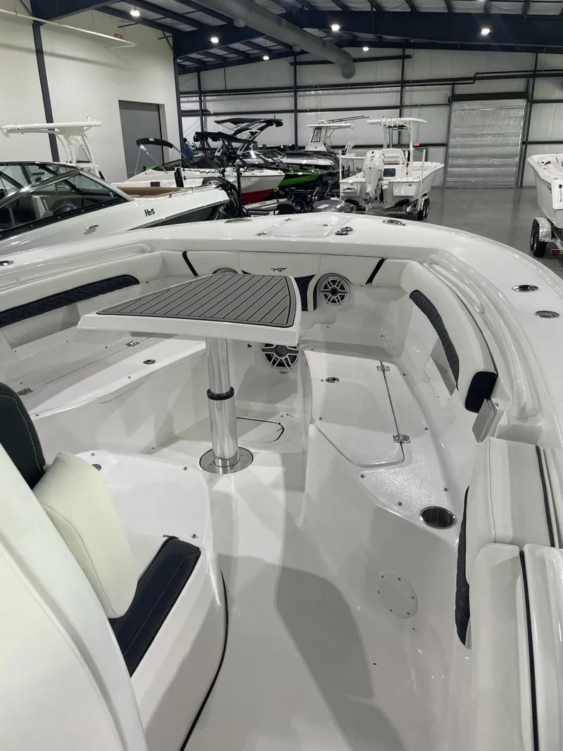 Slide: The Image of 2025 Tidewater 272 boat interior with seating and table in a showroom. - 2