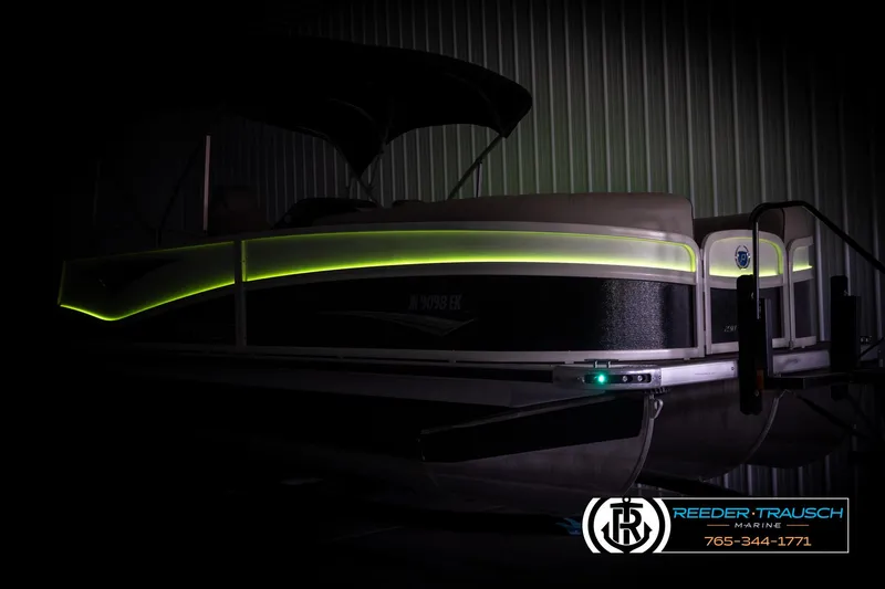 Slide: The Image of 2022 Premier 230 Solaris RL pontoon boat with illuminated side paneling in a dimly lit setting. - 4