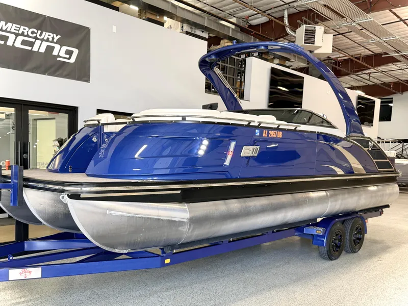 Slide: The Image of 2021 Bennington QX25 pontoon boat in showroom, blue exterior, on trailer. - 0