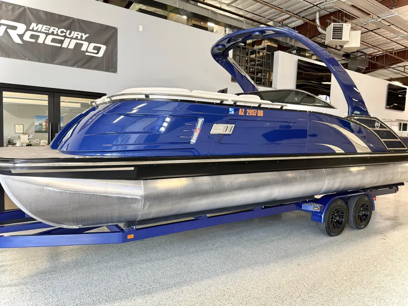 Slide: The Image of 2021 Bennington QX25 pontoon boat in showroom, blue exterior, on trailer. - 1