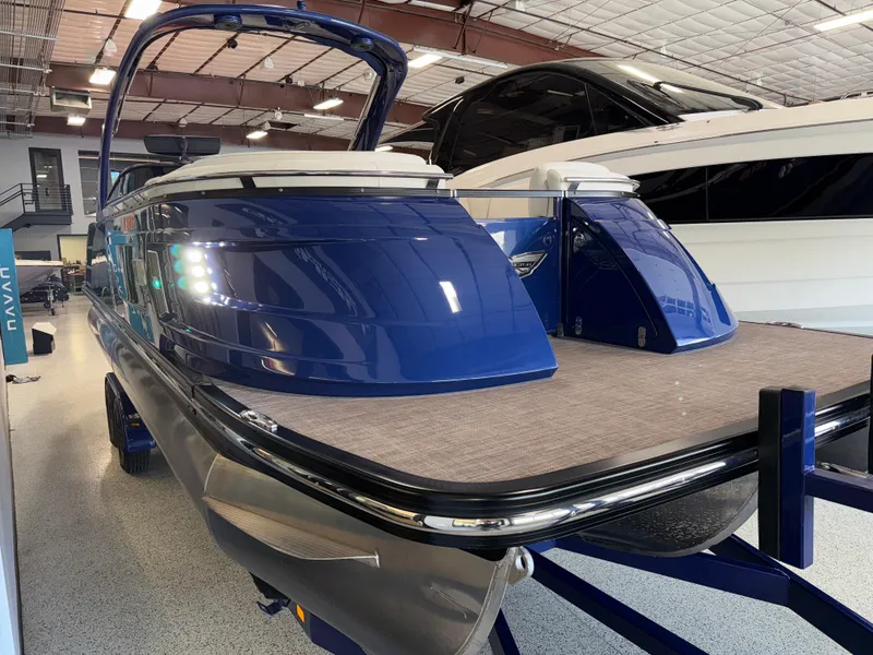 Slide: The Image of 2021 Bennington QX25 pontoon boat in showroom, featuring sleek blue design and modern amenities. - 11