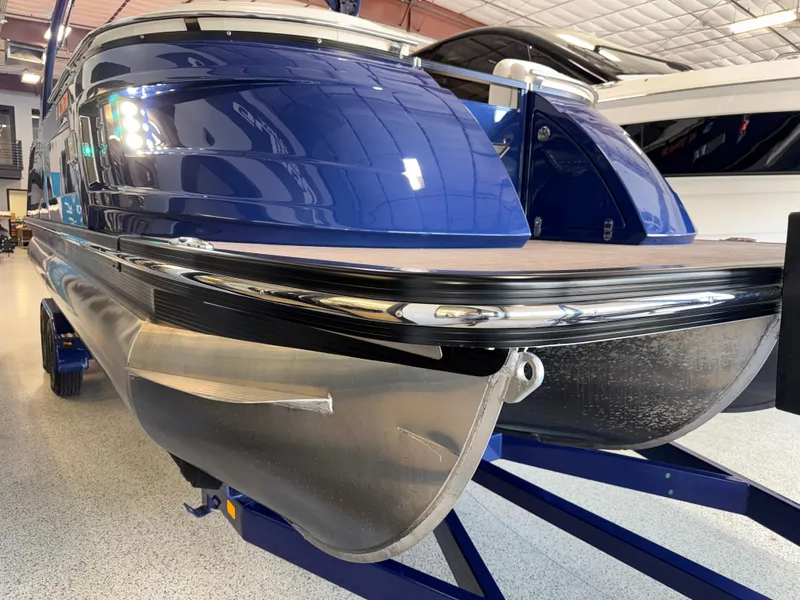 Slide: The Image of 2021 Bennington QX25 pontoon boat in showroom, featuring sleek blue design and modern detailing. - 12