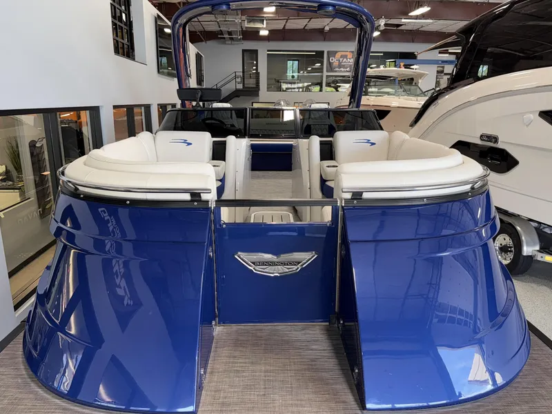 Slide: The Image of 2021 Bennington QX25 pontoon boat with blue exterior and white seating in showroom. - 14