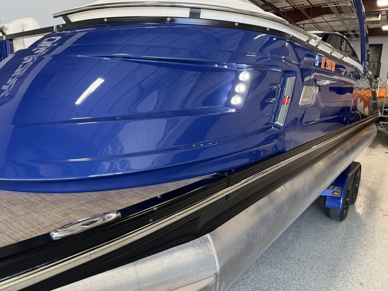 Slide: The Image of 2021 Bennington QX25 pontoon boat with sleek blue exterior in showroom. - 2