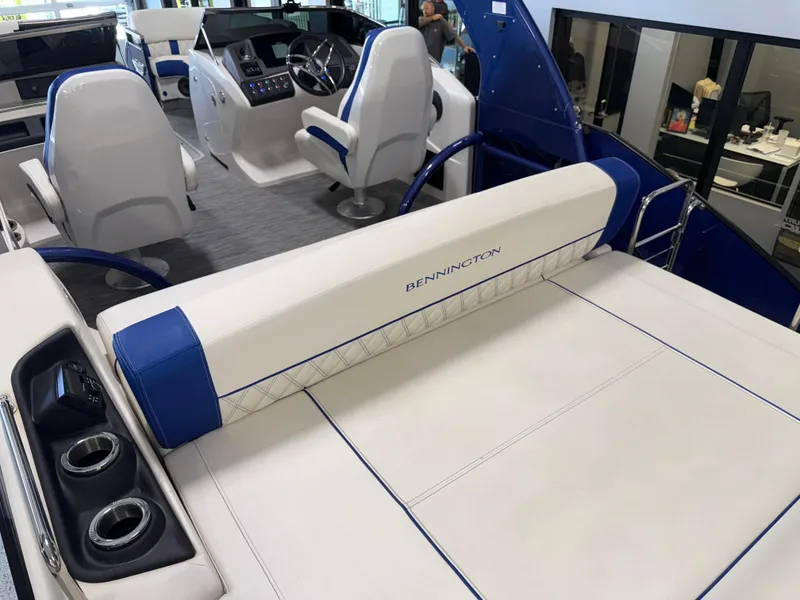 Slide: The Image of 2021 Bennington QX25 boat interior with white and blue seating, modern helm, and cup holders. - 31