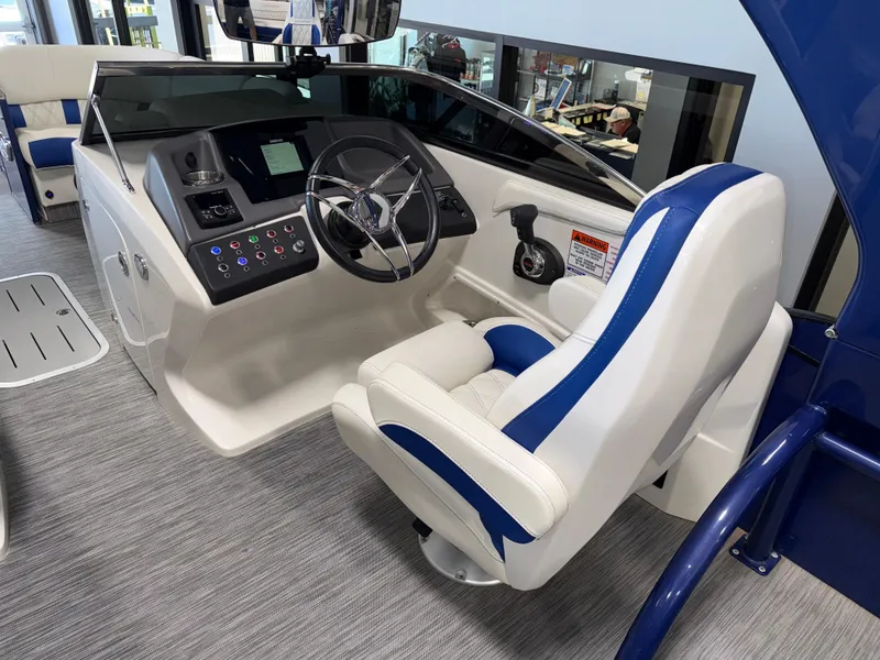Slide: The Image of 2021 Bennington QX25 boat helm with modern controls and blue-accented captain's chair. - 34