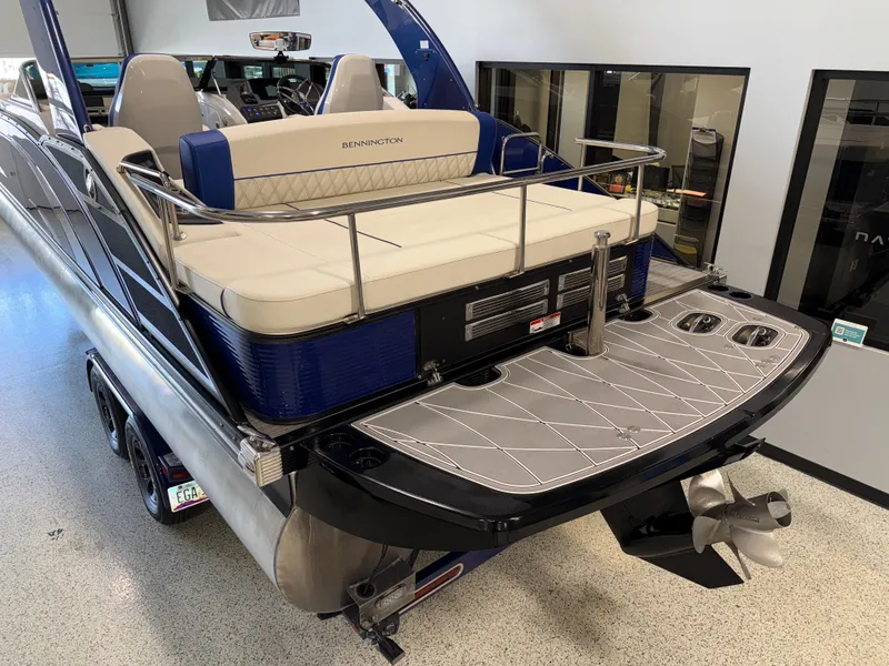 Slide: The Image of 2021 Bennington QX25 pontoon boat with luxurious seating and sleek design in a showroom. - 5