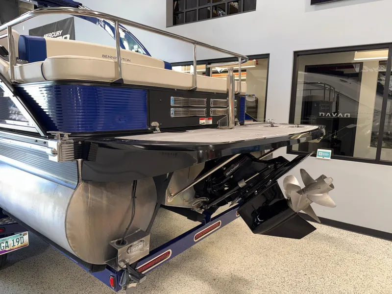 Slide: The Image of 2021 Bennington QX25 pontoon boat with outboard motor, displayed indoors. - 6