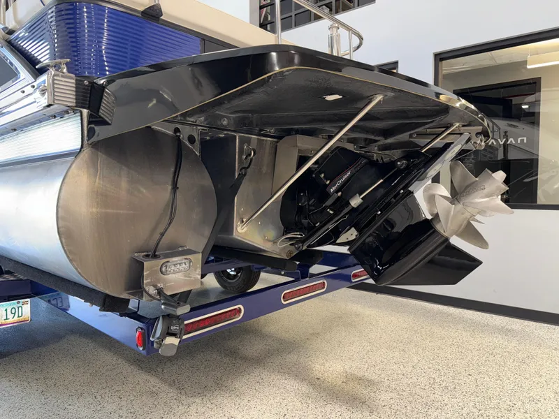 Slide: The Image of 2021 Bennington QX25 pontoon boat with visible propeller and motor, displayed indoors. - 7