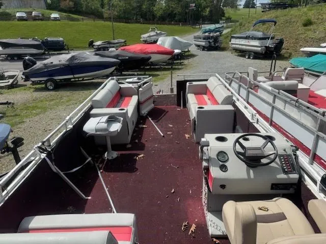 Slide: The Image of 1988 Skipper Craft 240 pontoon boat with red and white seating, parked among other boats. - 6