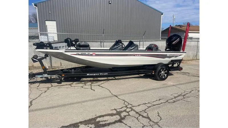 Slide: The Image of 2018 Ranger RT198P fishing boat on trailer, parked outdoors near a metal building. - 2