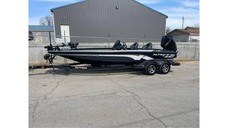 Slide: The Image of 2022 Nitro Z21 XL boat on trailer, parked outdoors near a gray building. - 2