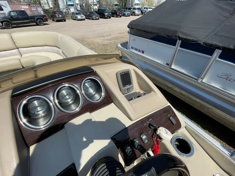 Slide: The Image of 2013 Bennington 2275 RCW boat dashboard with gauges and controls, parked outdoors. - 15
