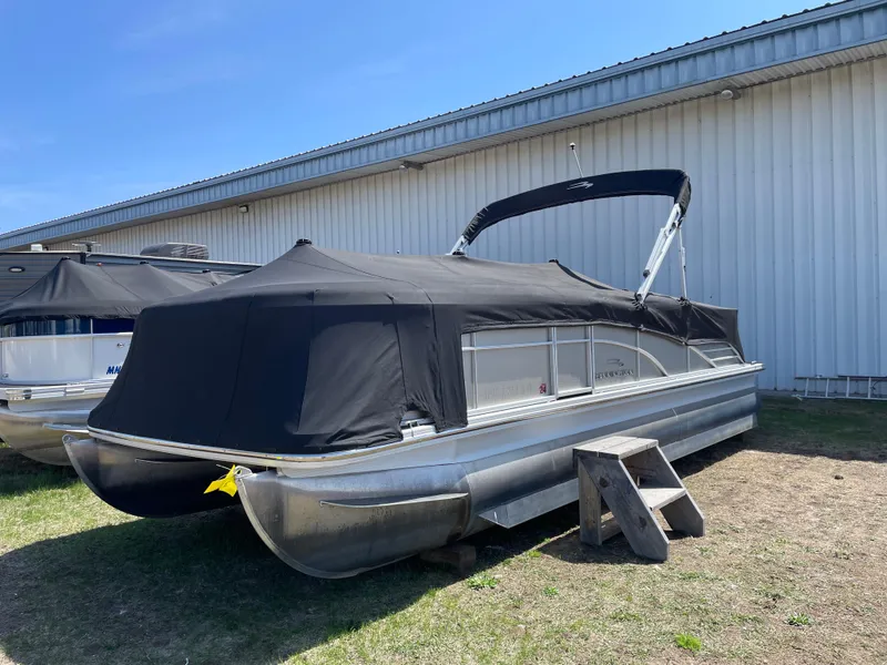 Slide: The Image of 2013 Bennington 2275 RCW pontoon boat with black cover, parked outdoors. - 18