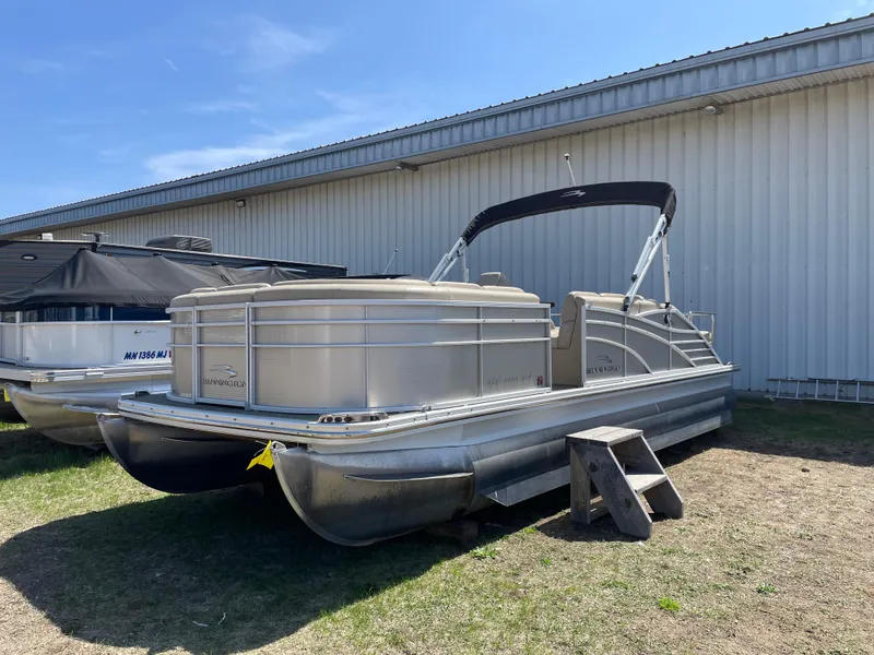 Slide: The Image of 2013 Bennington 2275 RCW pontoon boat parked outdoors near a metal building. - 2