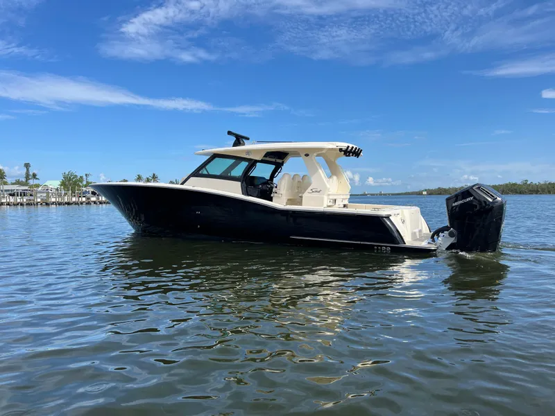 Slide: The Image of 2025 Scout 425 LXF boat on calm water under clear blue sky. - 2