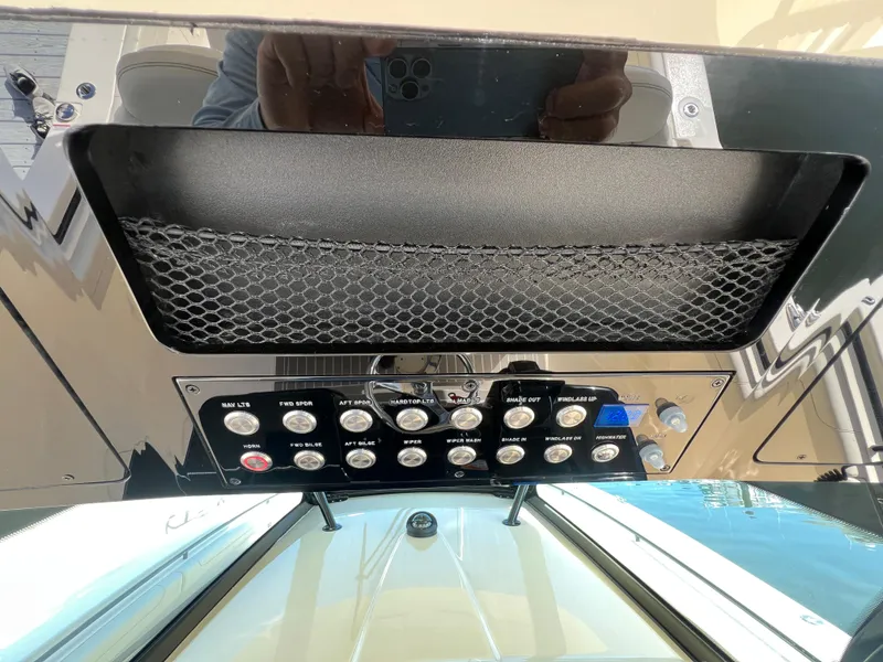 Slide: The Image of Control panel of 2025 Scout 425 LXF boat with various switches and netted storage. - 22