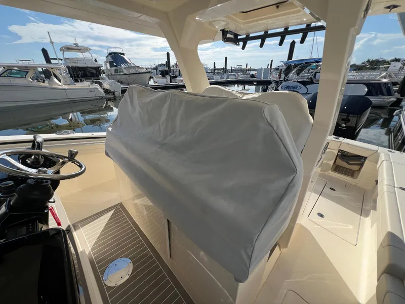 Slide: The Image of 2025 Scout 425 LXF boat interior with covered seating at a marina. - 46