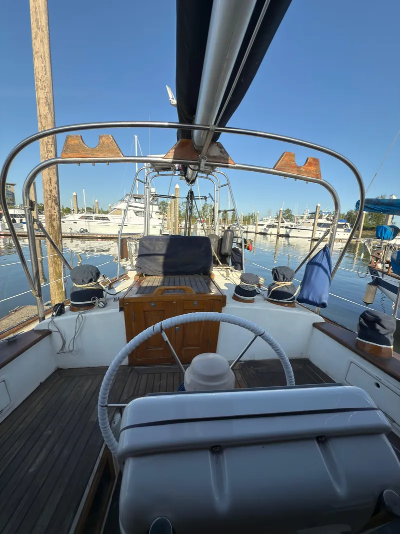 Slide: The Image of 1984 Spindrift Cutter sailboat cockpit with steering wheel, docked at marina. - 13