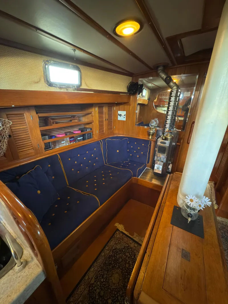 Slide: The Image of 1984 Spindrift Cutter yacht interior with blue seating, wood paneling, and nautical decor. - 16