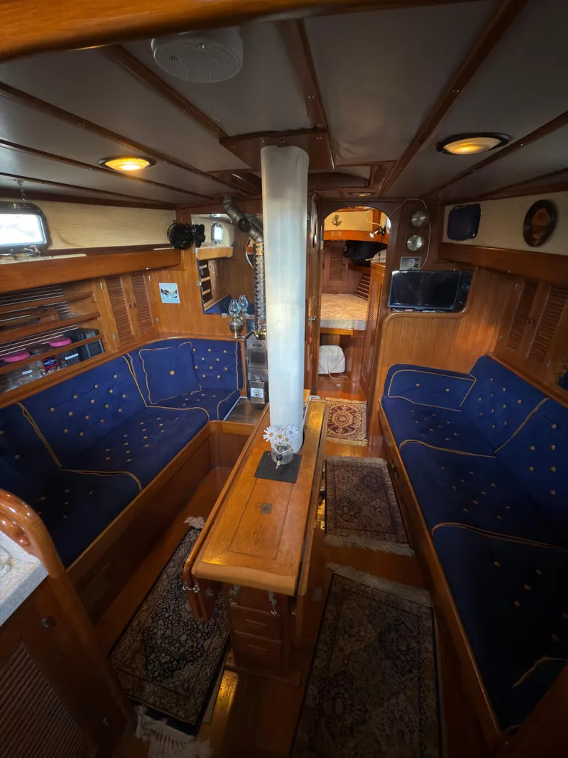 Slide: The Image of 1984 Spindrift Cutter yacht interior with blue seating, wooden accents, and cozy cabin layout. - 18