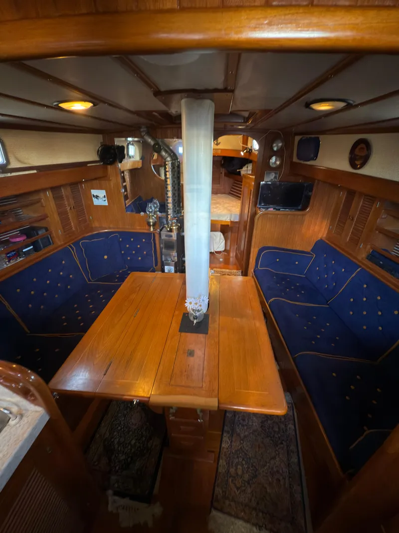 Slide: The Image of 1984 Spindrift Cutter interior with wooden dining area and blue cushioned seating. - 19