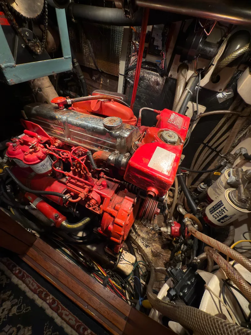 Slide: The Image of Engine room of a 1984 Spindrift Cutter sailboat, featuring a red marine engine. - 26
