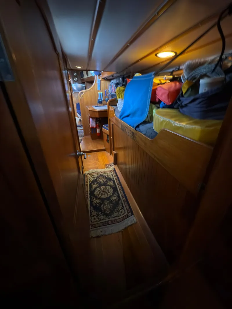 Slide: The Image of Narrow wooden hallway inside 1984 Spindrift Cutter sailboat, featuring storage and cozy lighting. - 27