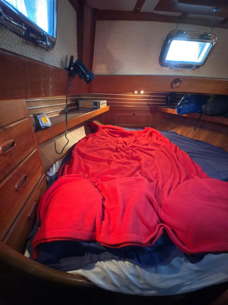 Slide: The Image of Cozy cabin interior of 1984 Spindrift Cutter with red blanket and wooden furnishings. - 29