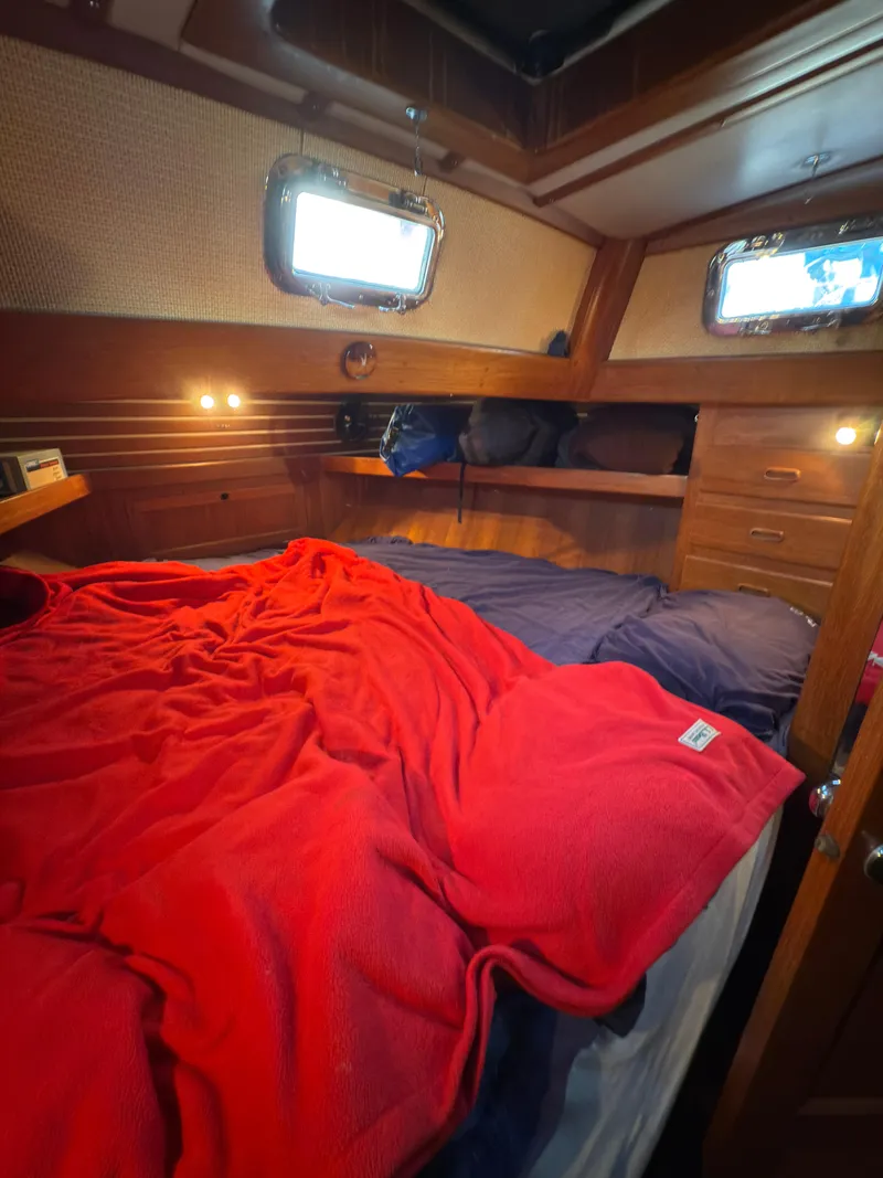 Slide: The Image of Cozy cabin interior of 1984 Spindrift Cutter with red blanket and wooden furnishings. - 30