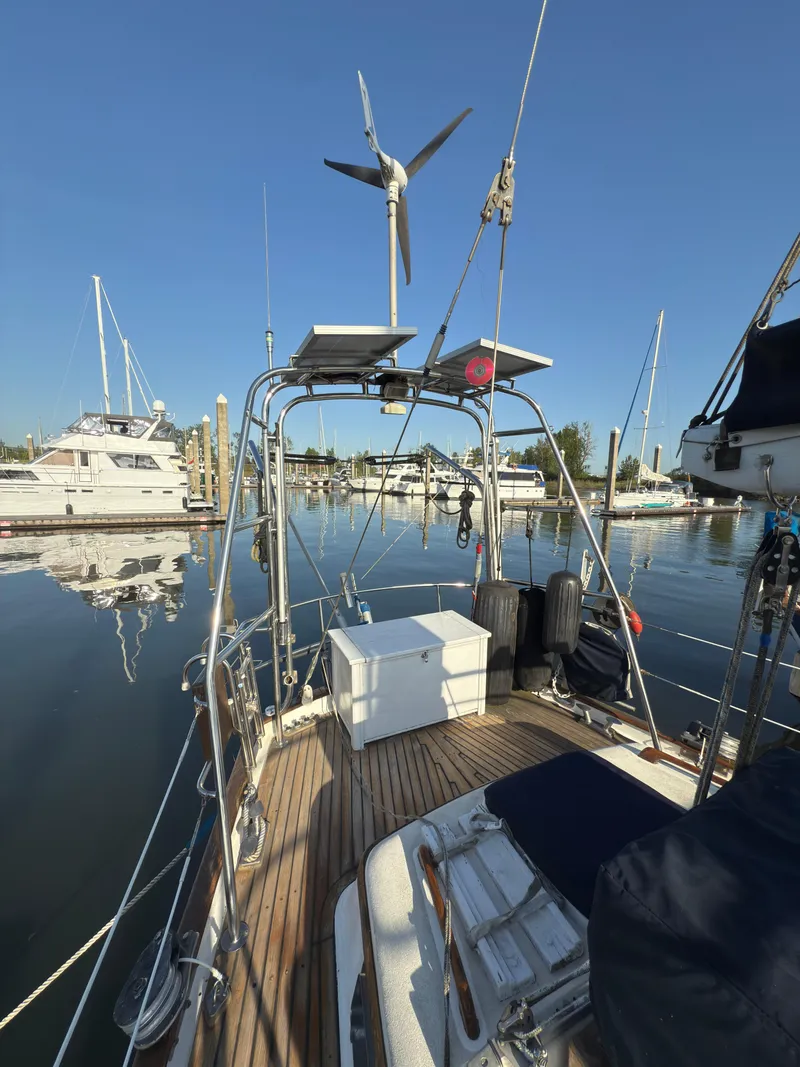 Slide: The Image of 1984 Spindrift Cutter sailboat with wind turbine, docked in a marina under clear blue skies. - 9