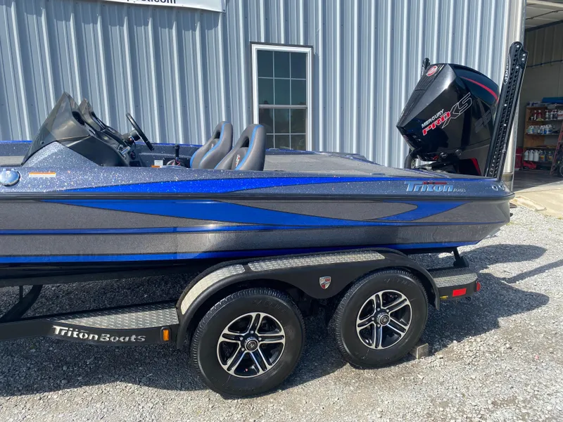 Slide: The Image of 2019 Triton 20 TRX Patriot boat on trailer, blue and gray design, parked outside a building. - 8