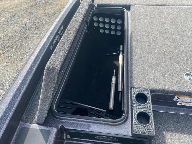 Slide: The Image of 2020 Triton 21 TrX boat storage compartment with tools and cup holders. - 18