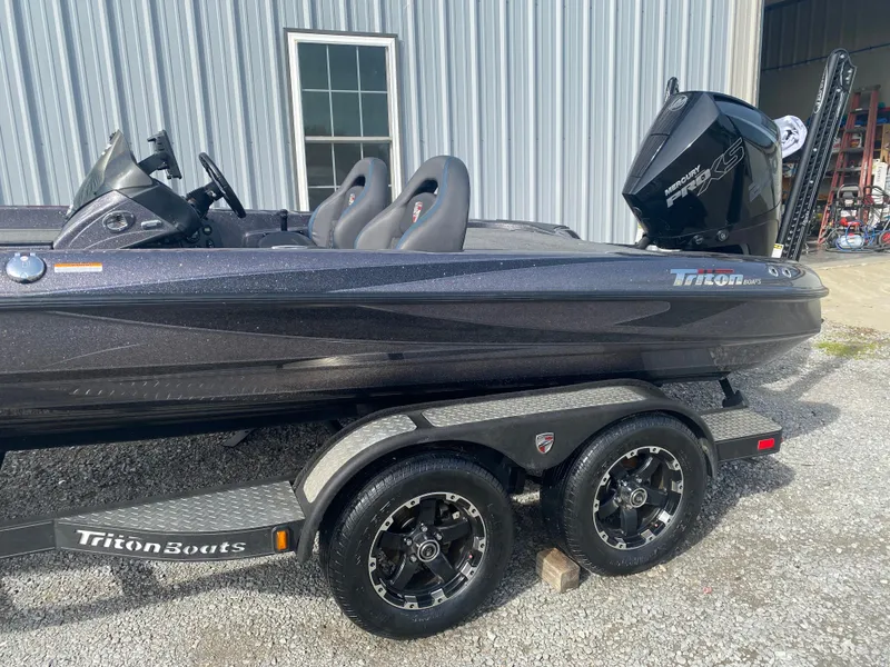 Slide: The Image of 2020 Triton 21 TrX boat on trailer, parked outside a metal building. - 9