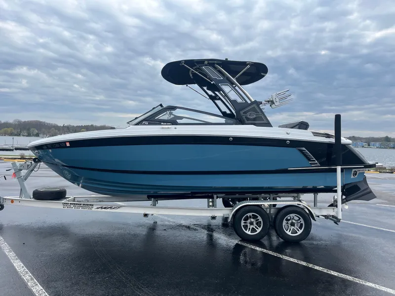 Slide: The Image of 2023 Cobalt R4 Surf boat on trailer, parked in a lot with cloudy sky background. - 0