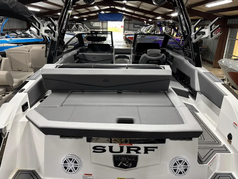 Slide: The Image of 2023 Cobalt R4 Surf boat interior, showcasing seating and deck features in a showroom. - 10