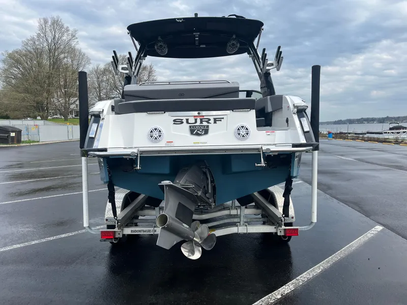 Slide: The Image of 2023 Cobalt R4 Surf boat on trailer, rear view, parked near waterfront. - 5