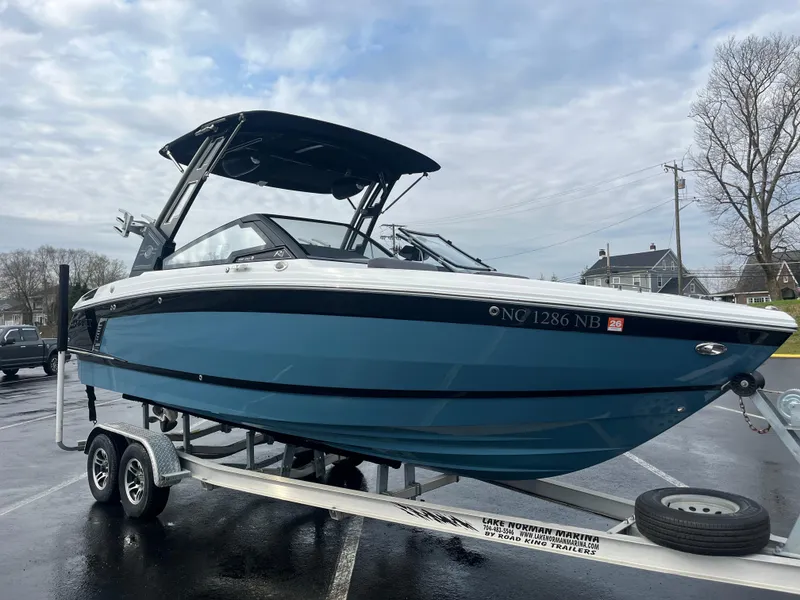 Slide: The Image of 2023 Cobalt R4 Surf boat on trailer, blue hull, parked outdoors. - 9