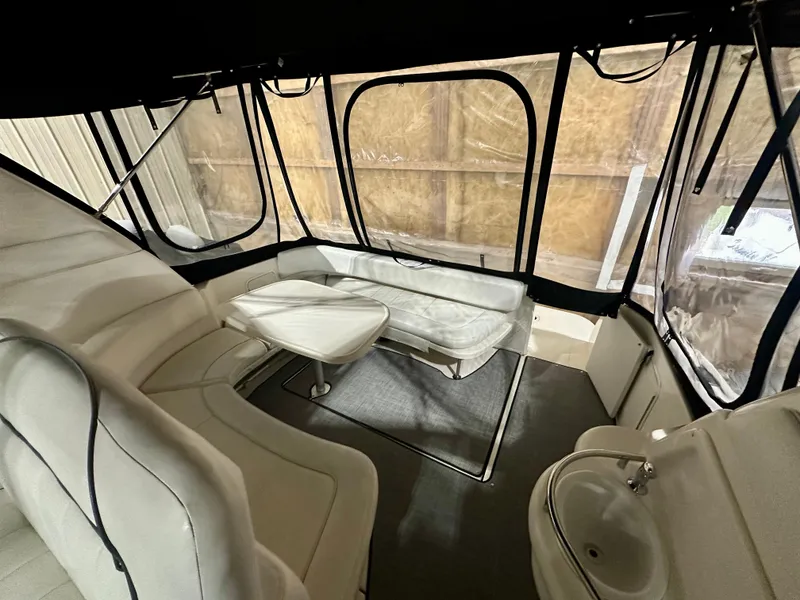 Slide: The Image of 1999 Sea Ray 310 Sundancer interior with seating, table, and sink in enclosed cabin. - 10